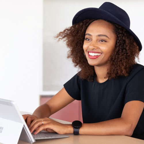 Female student is sitting at her desk with a laptop, smiling