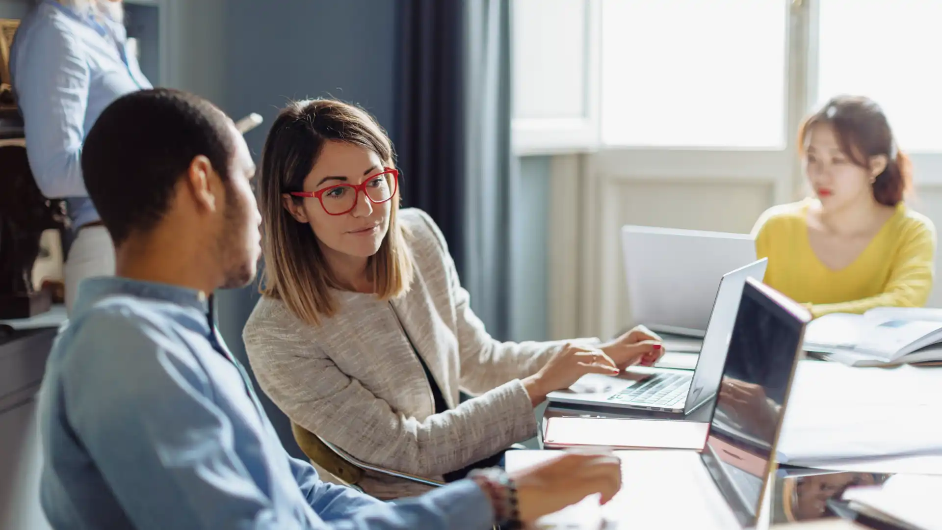 Two professionals working on laptops