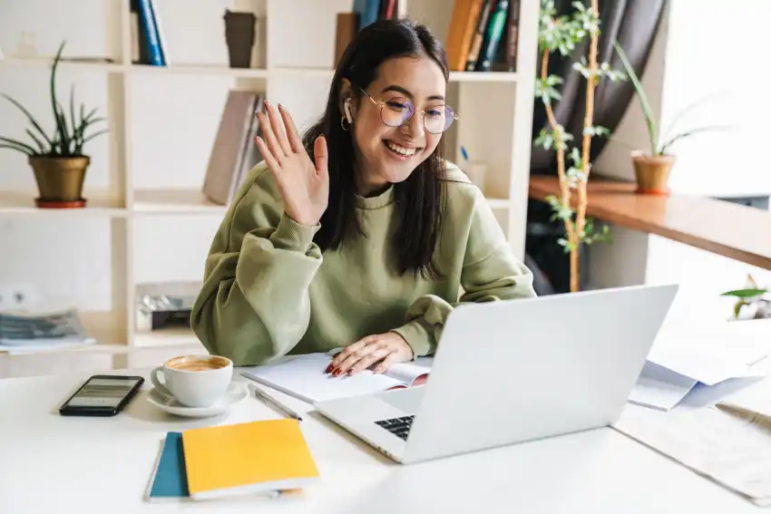 A woman waving at the laptop.